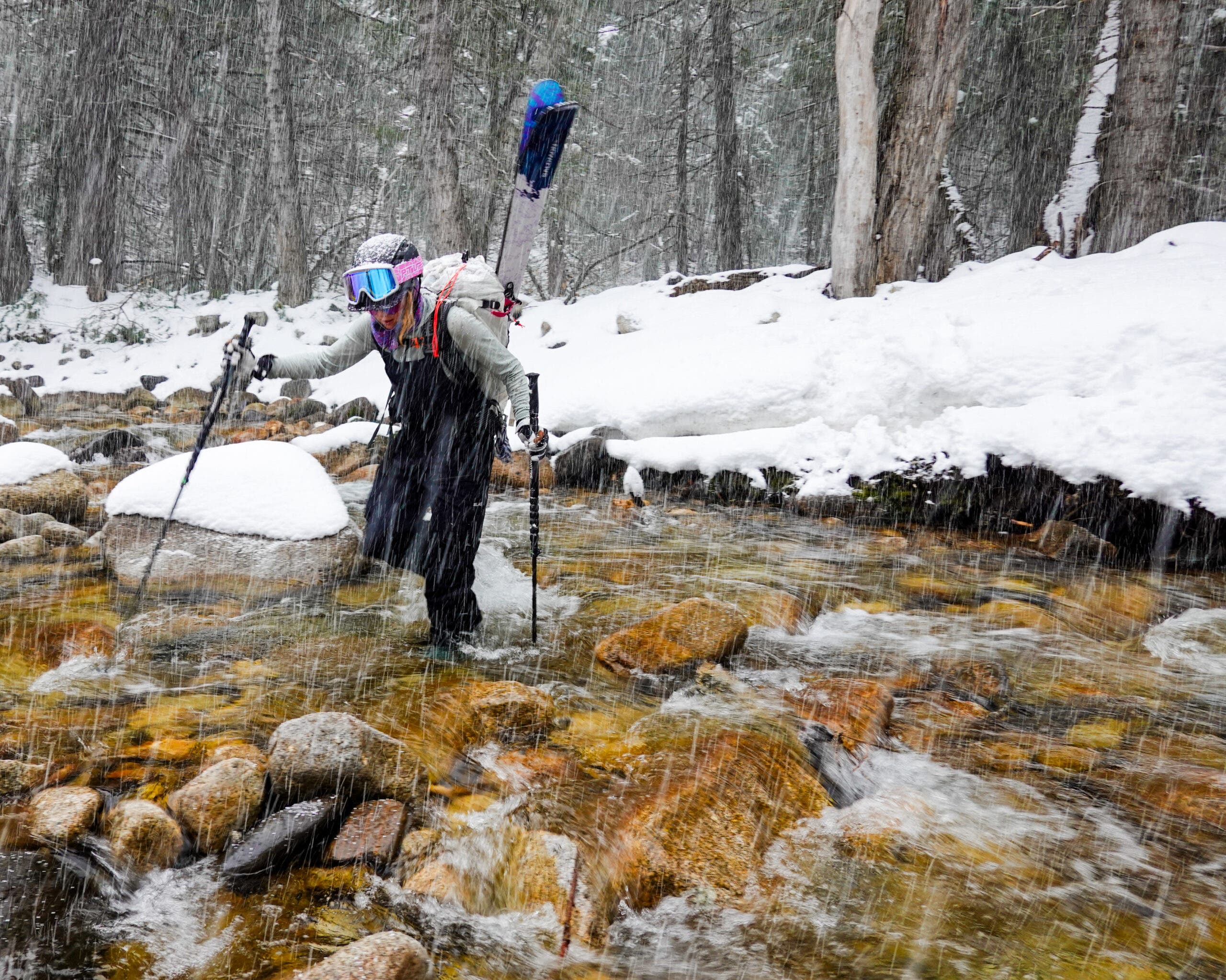 A skier crossing a creek in a storm