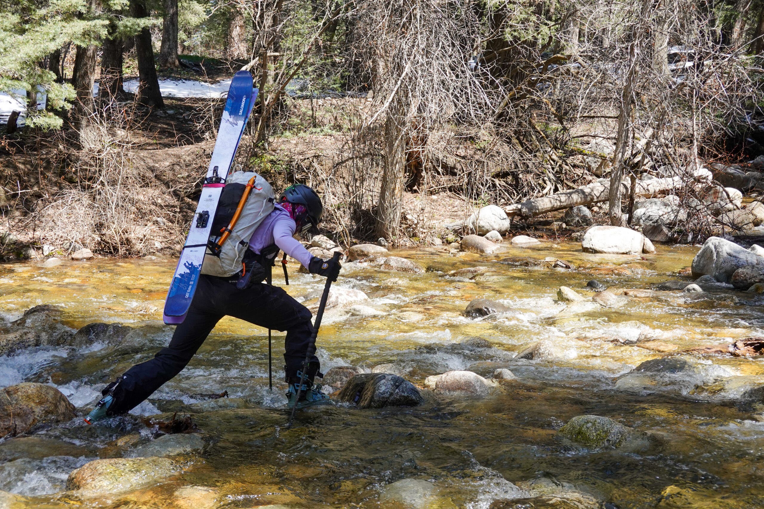 Mali Noyes crosses a creek in ski boots.