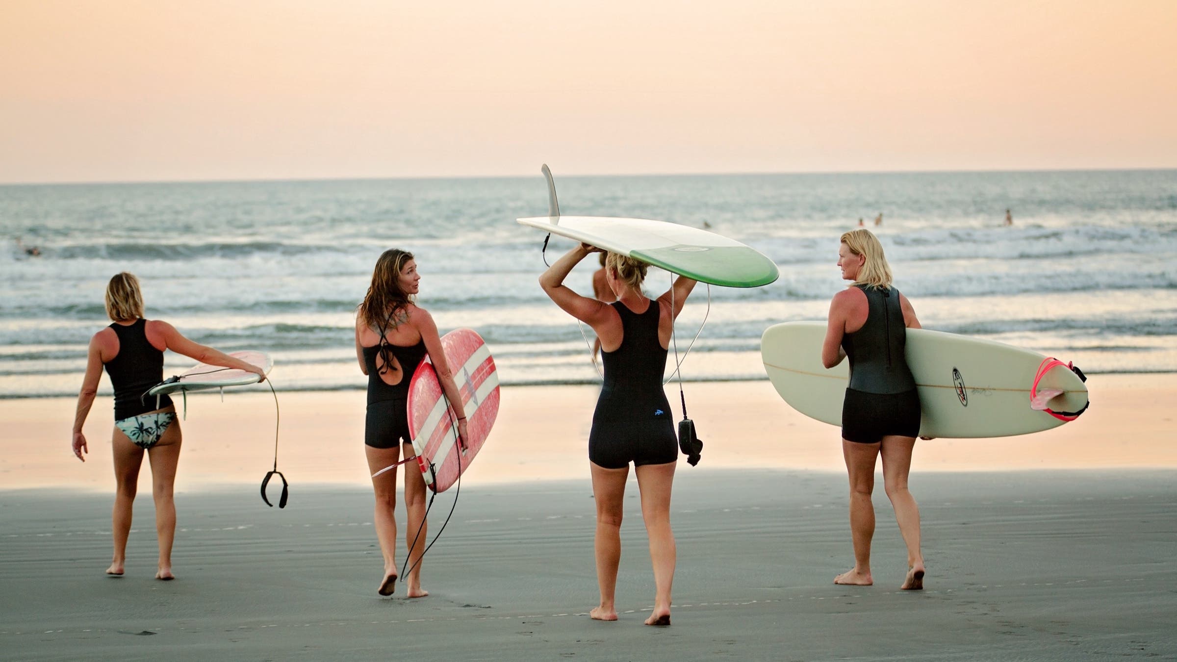 Women walking on beach to go surf