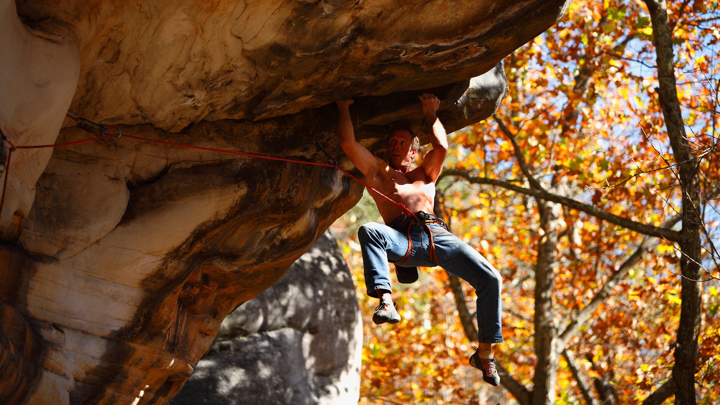 A climber works on solving the cruxy roof of Great White Shark (5.12c) at Bubba City in the New River Gorge near Fayetteville, West Virginia