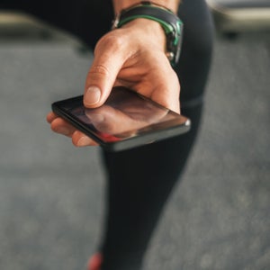 Sporty male athlete looking his smartphone holding water bottle.