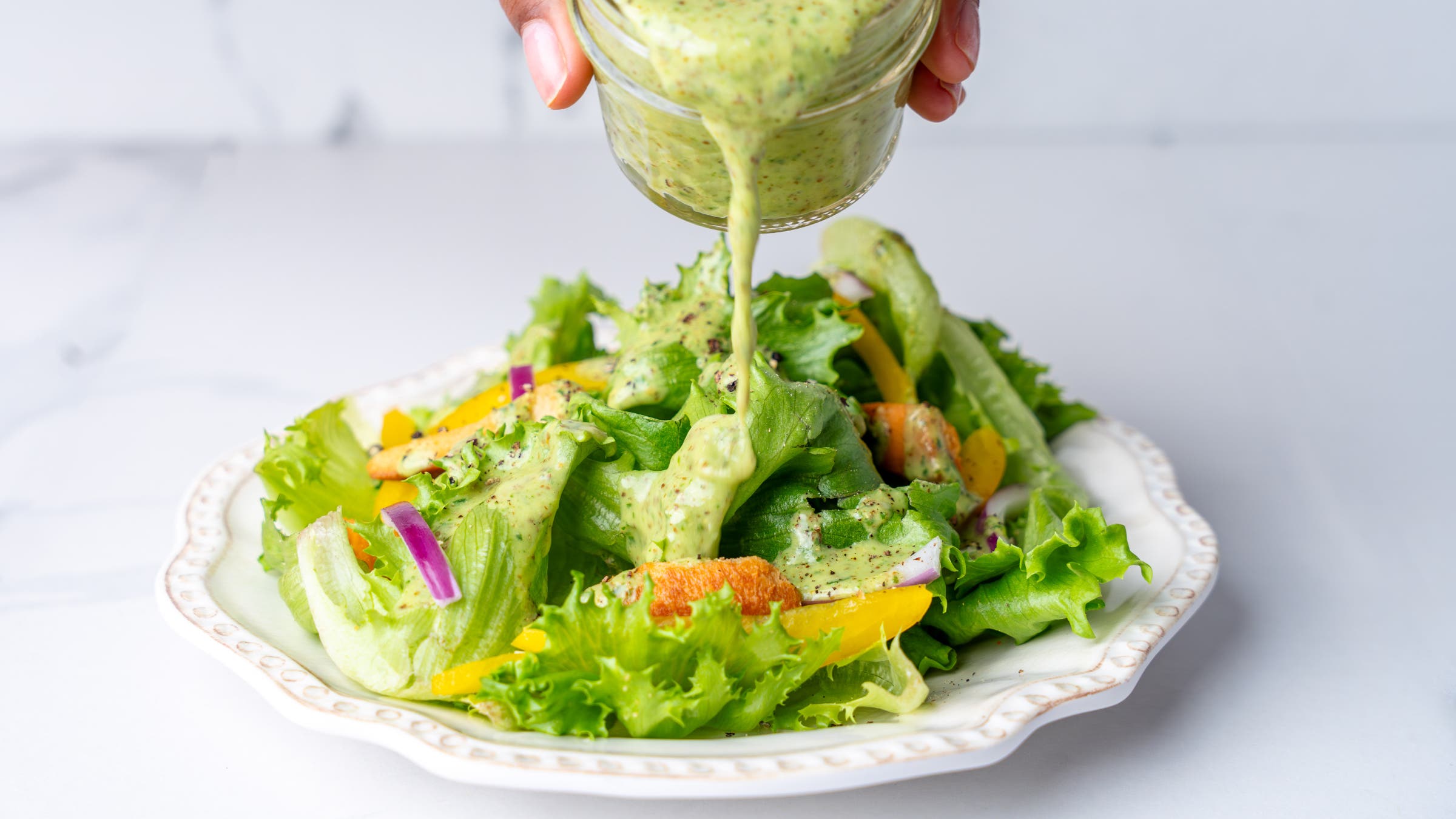 Green aloe vera gel salad dressing recipe poured on top of a lettuce salad