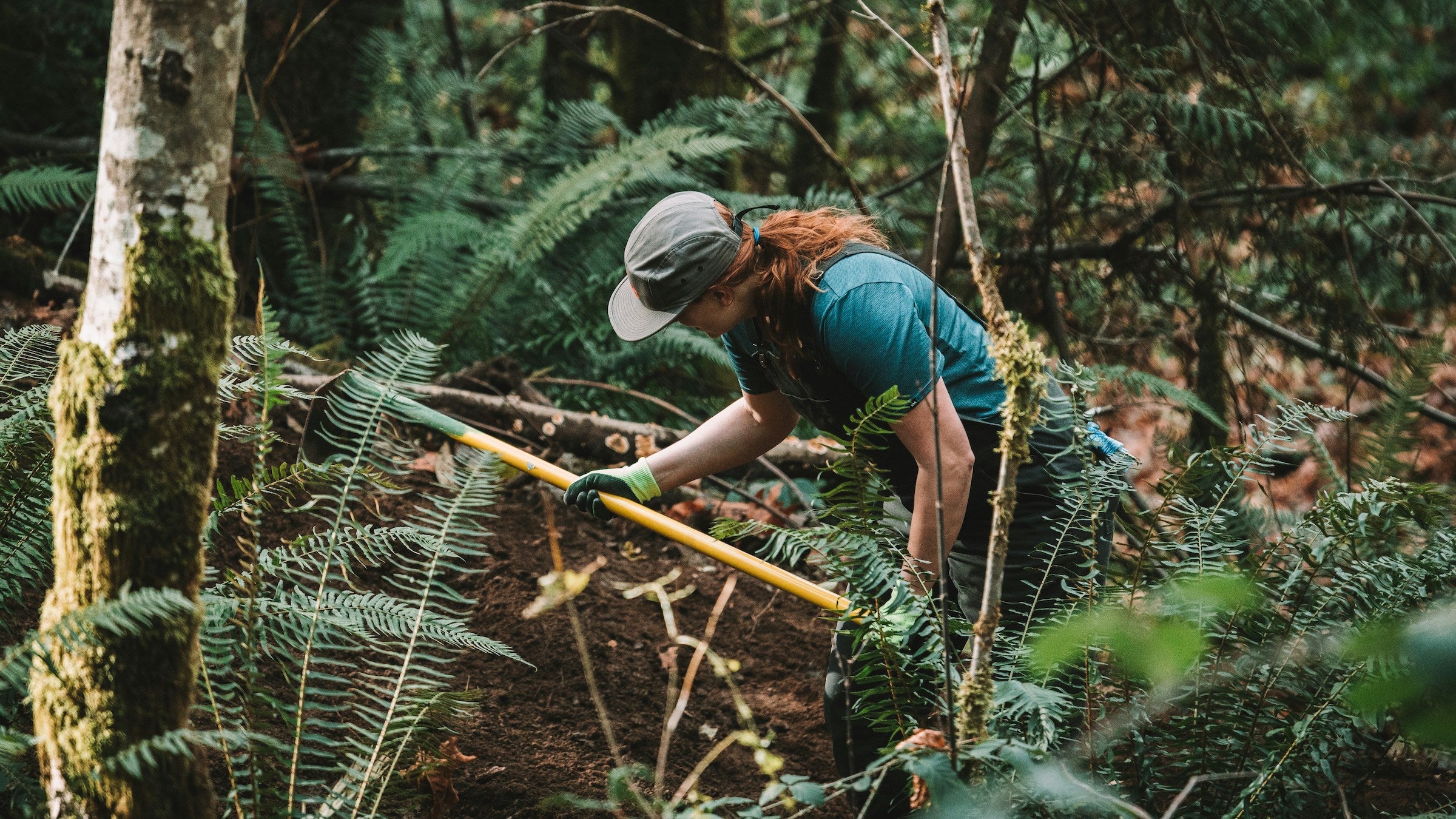 A woman doing trail work in a forest