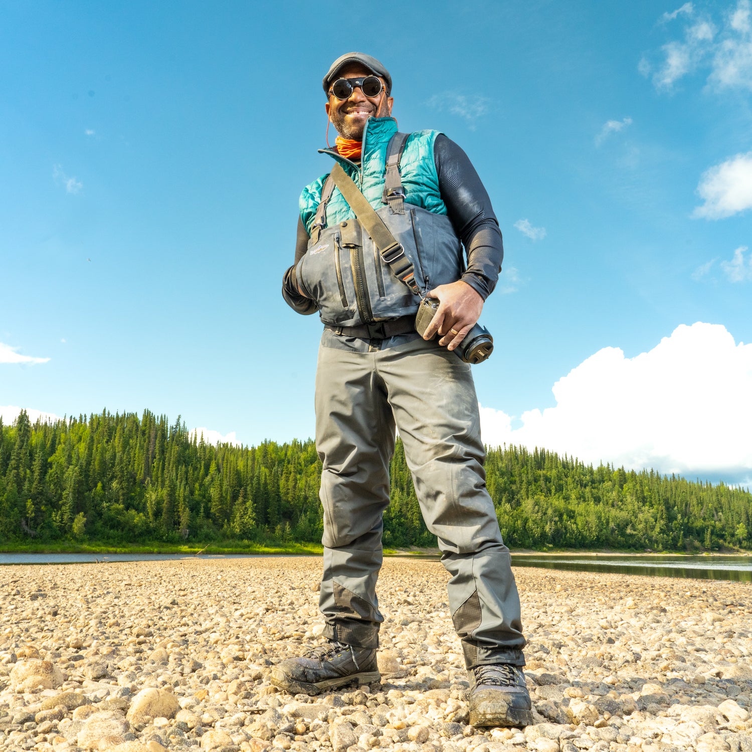 James Edward Mills in a national park wearing fishing gear and smiling under a blue sky