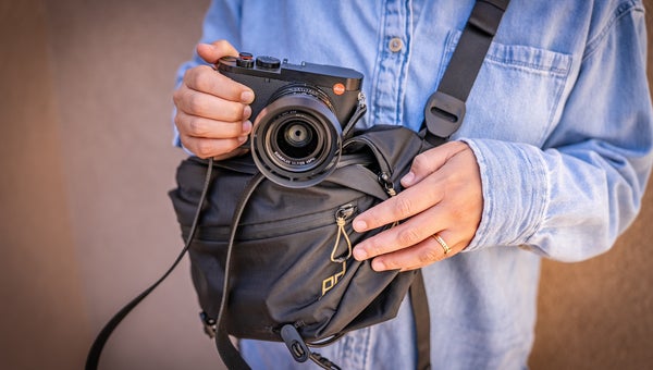 close-in photograph of a person in a chambray shirt holding one of the best camera bags