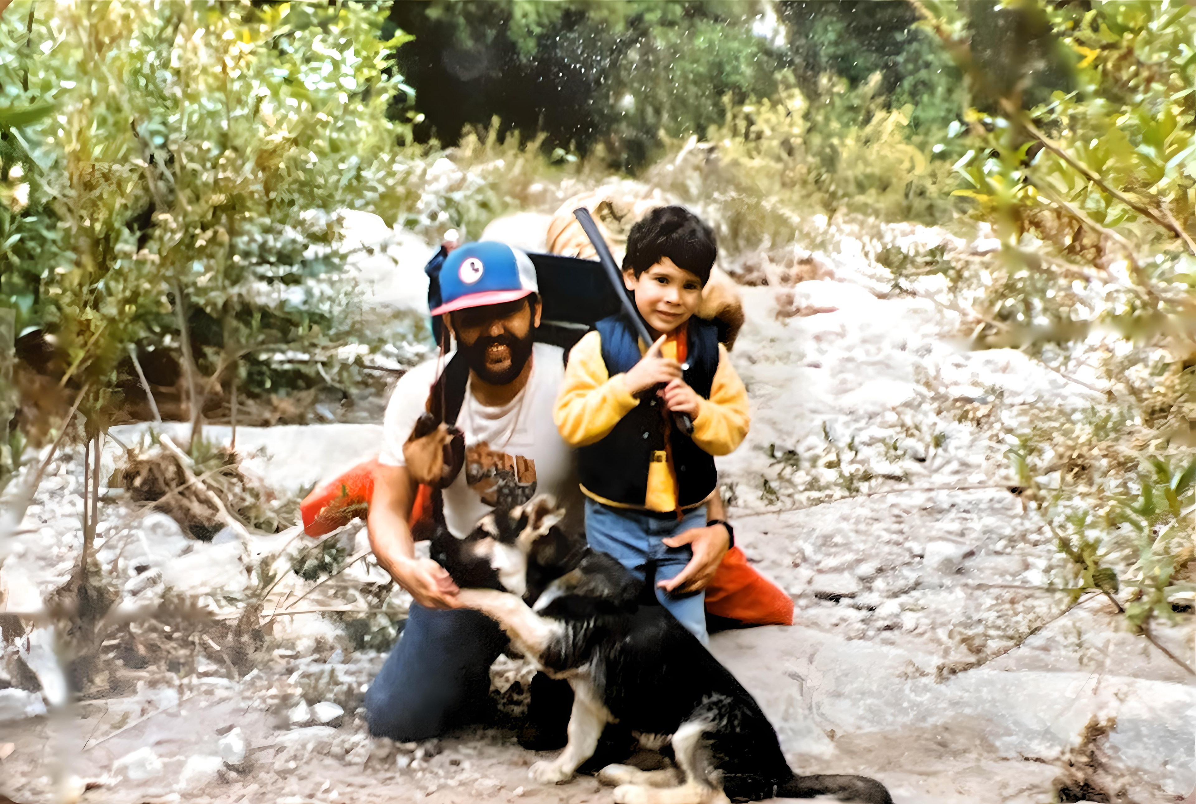 A young boy and his father pose with their dog on a camping trip