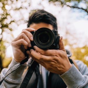 Closeup of young photographer hiking in forest and photographing nature.