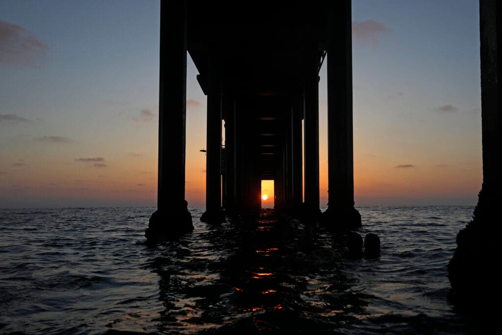 SAN DIEGO, CALIFORNIA - AUGUST 8: The sun aligns at sunset with the pillars of UC San Diego's Scripps Institution of Oceanography Ellen Browning Scripps Memorial Pier in a biannual phenomena known as scrippshenge on August 8, 2024 in San Diego, California. Twice a year, crowds gather on the beach to try to get a look at the sight. (Photo by Kevin Carter/Getty Images)