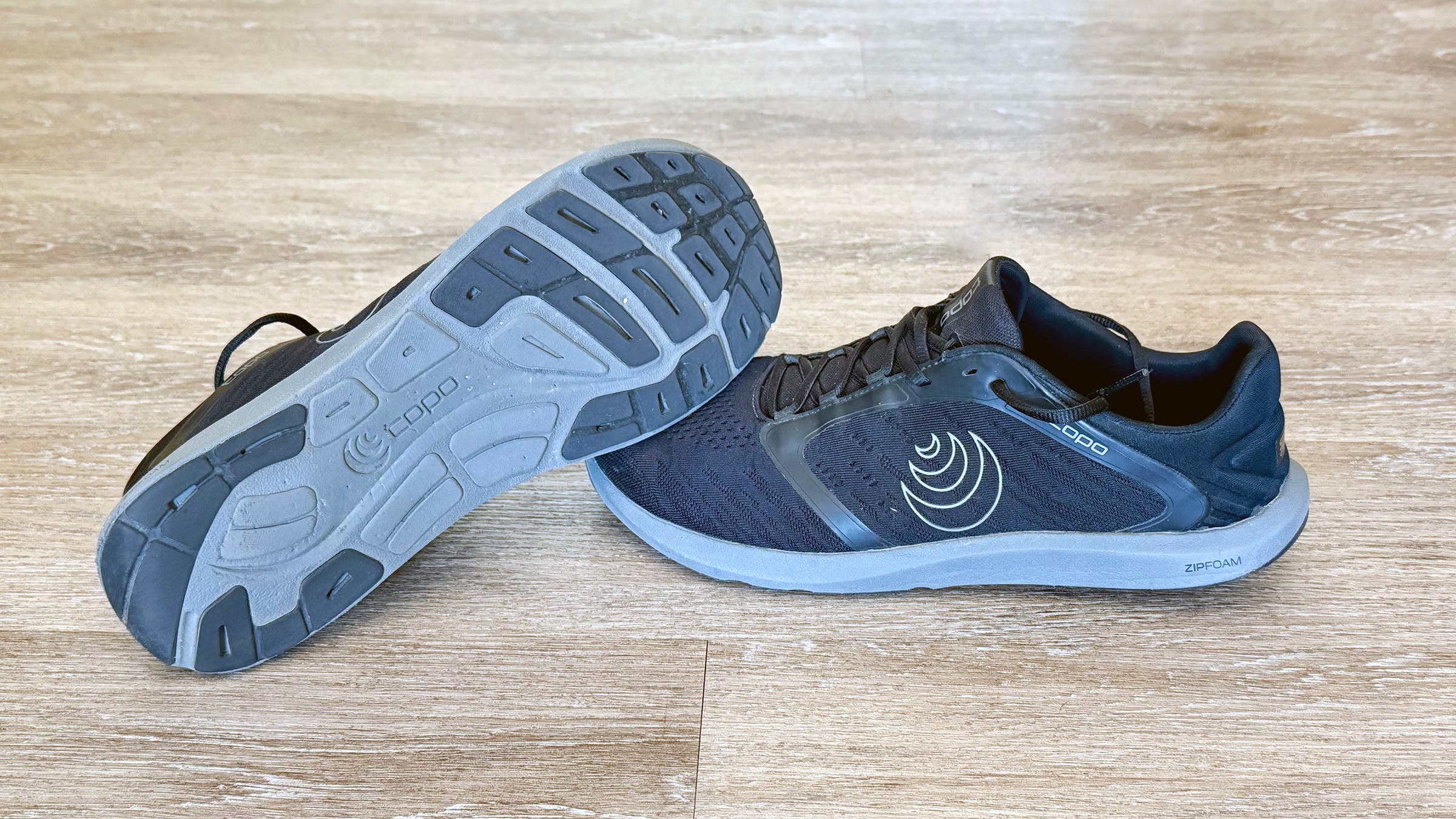 Topo ST5 running shoes displayed on wooden floor