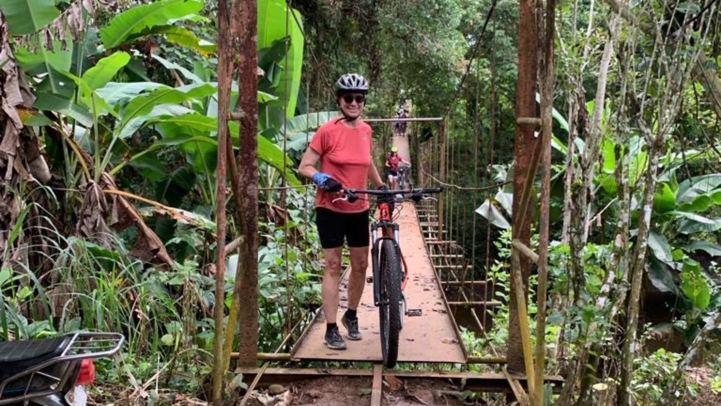 Woman crossing bridge with bike