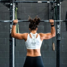 A woman lifting a large barbell over her head in an overhead press
