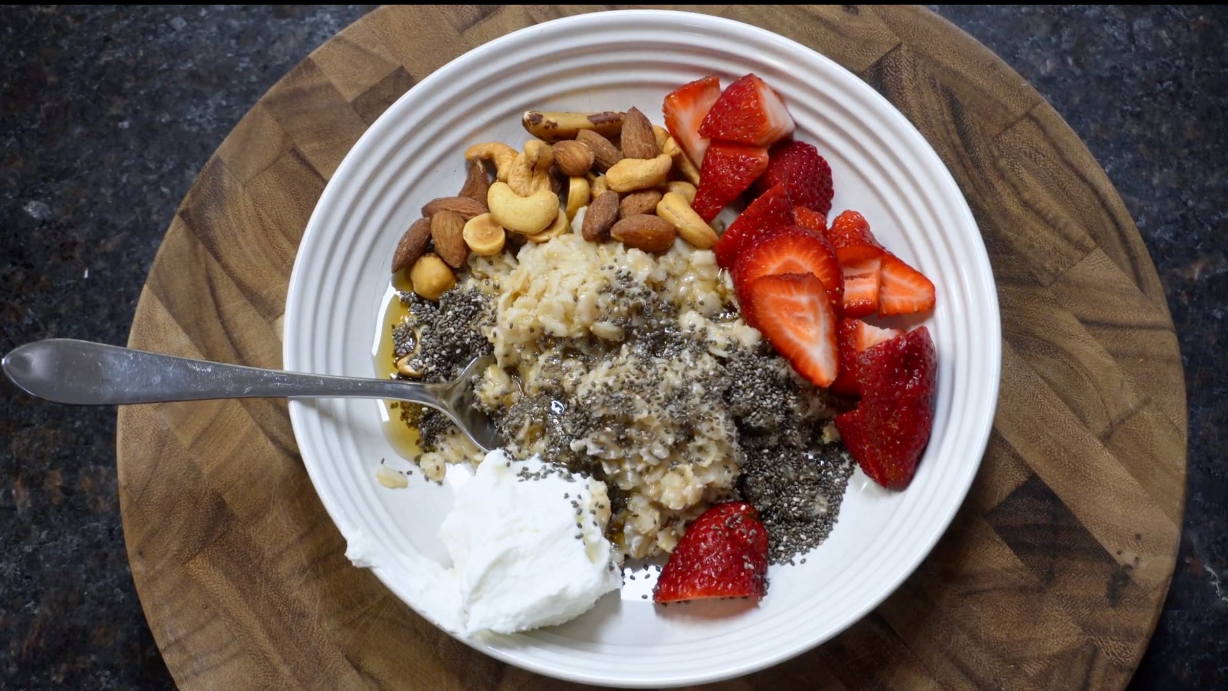 A bowl of oatmeal with strawberries, chia seeds, nuts, and Greek yogurt