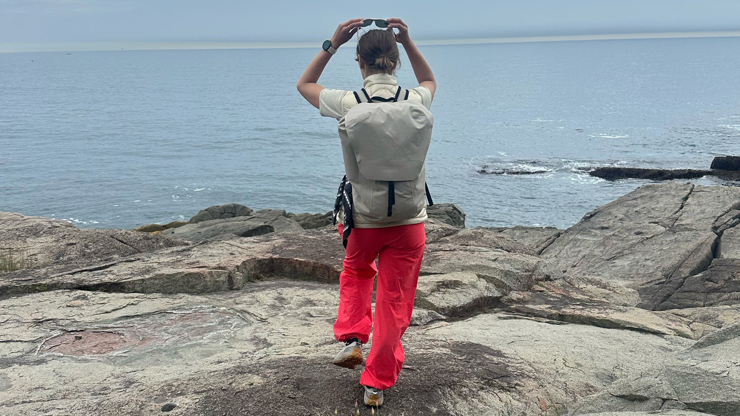 Woman hiker on coastal trail wearing white pack