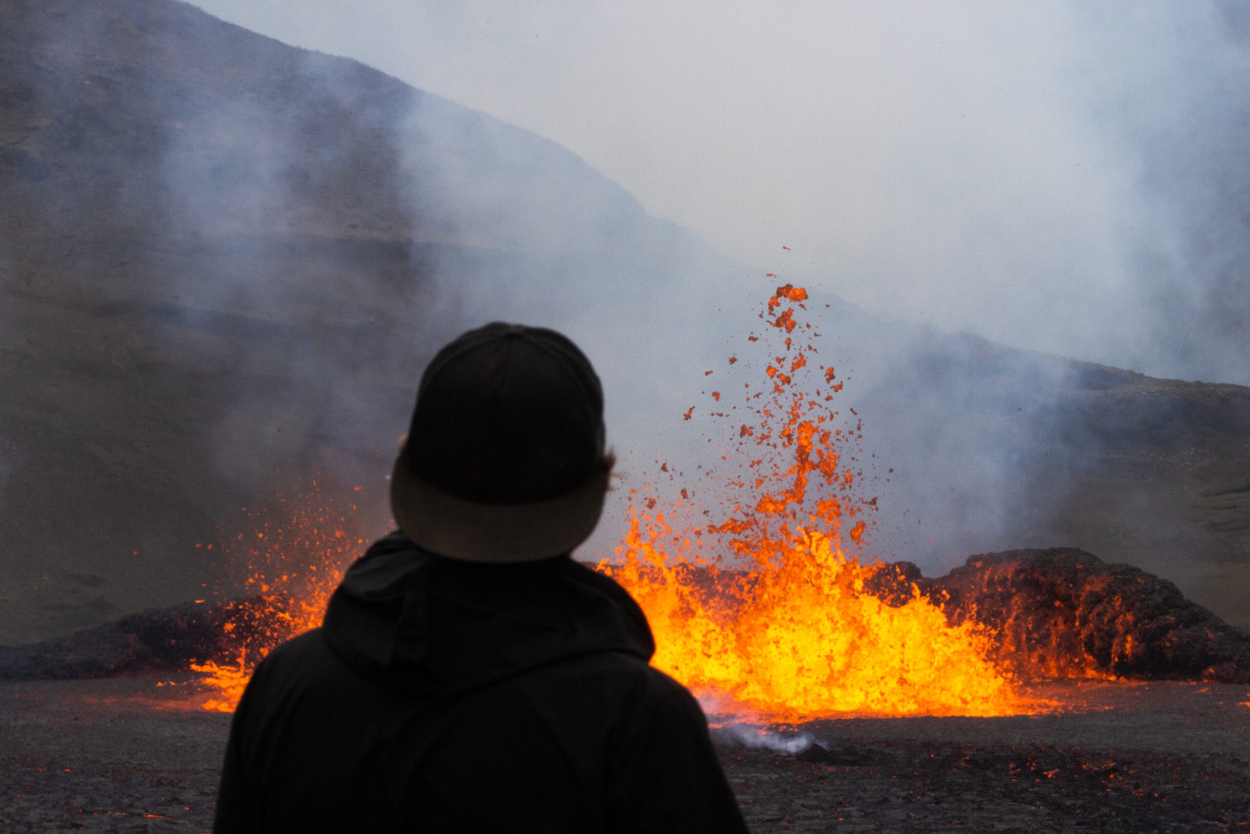 One tourist standing close to an erupting volcano, Iceland