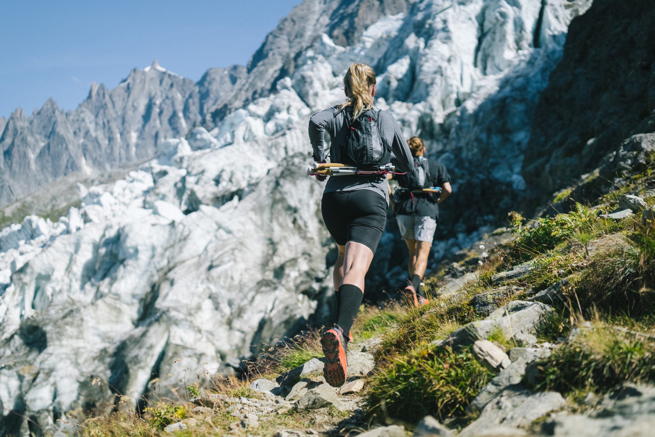 A trail runner bounds up the path below a glacier in Chamonix, France.