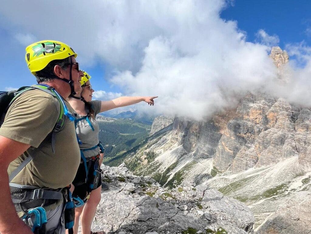 father and daughter stand on a mountain amid the clouds