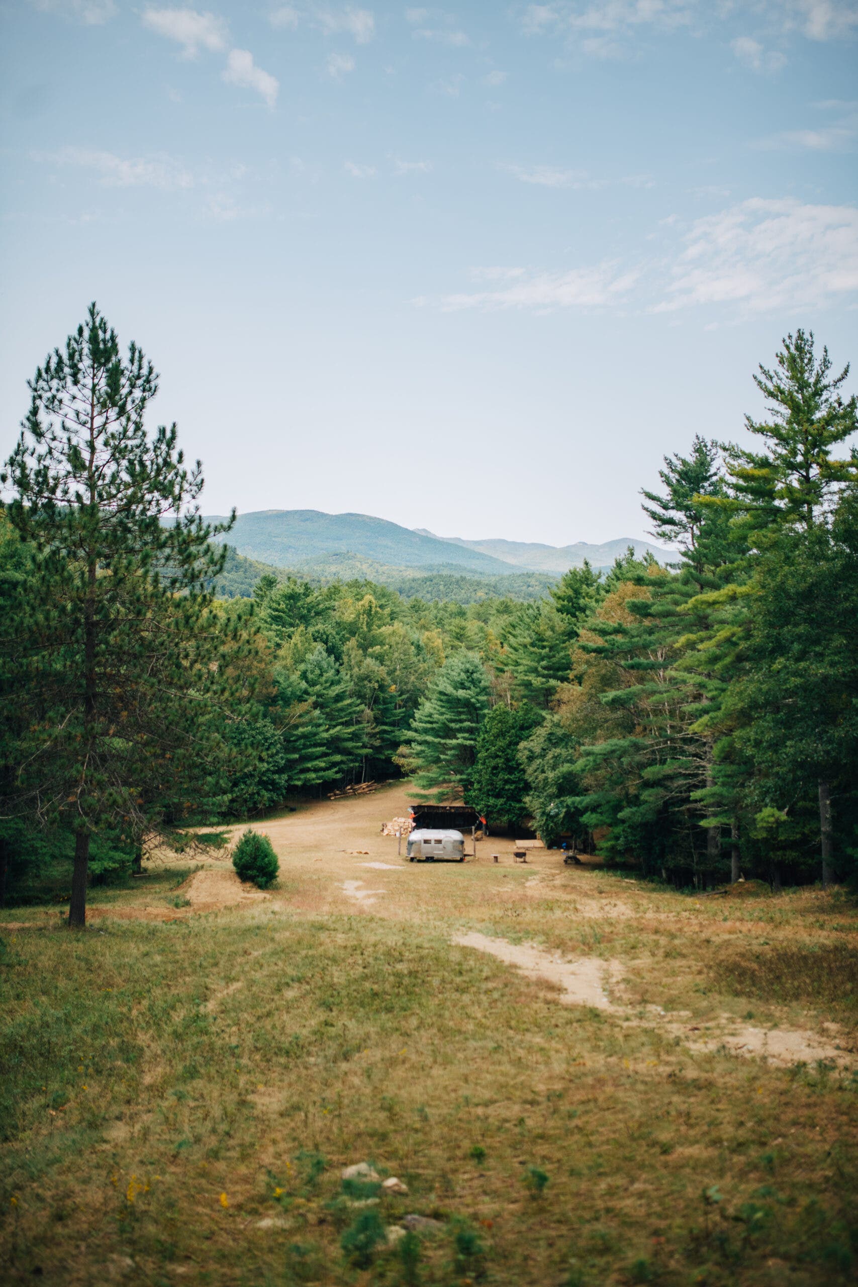 A camper sits in a field between the forest