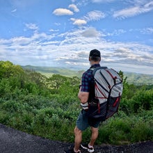 Hiker with backpack standing at lush overlook on trail