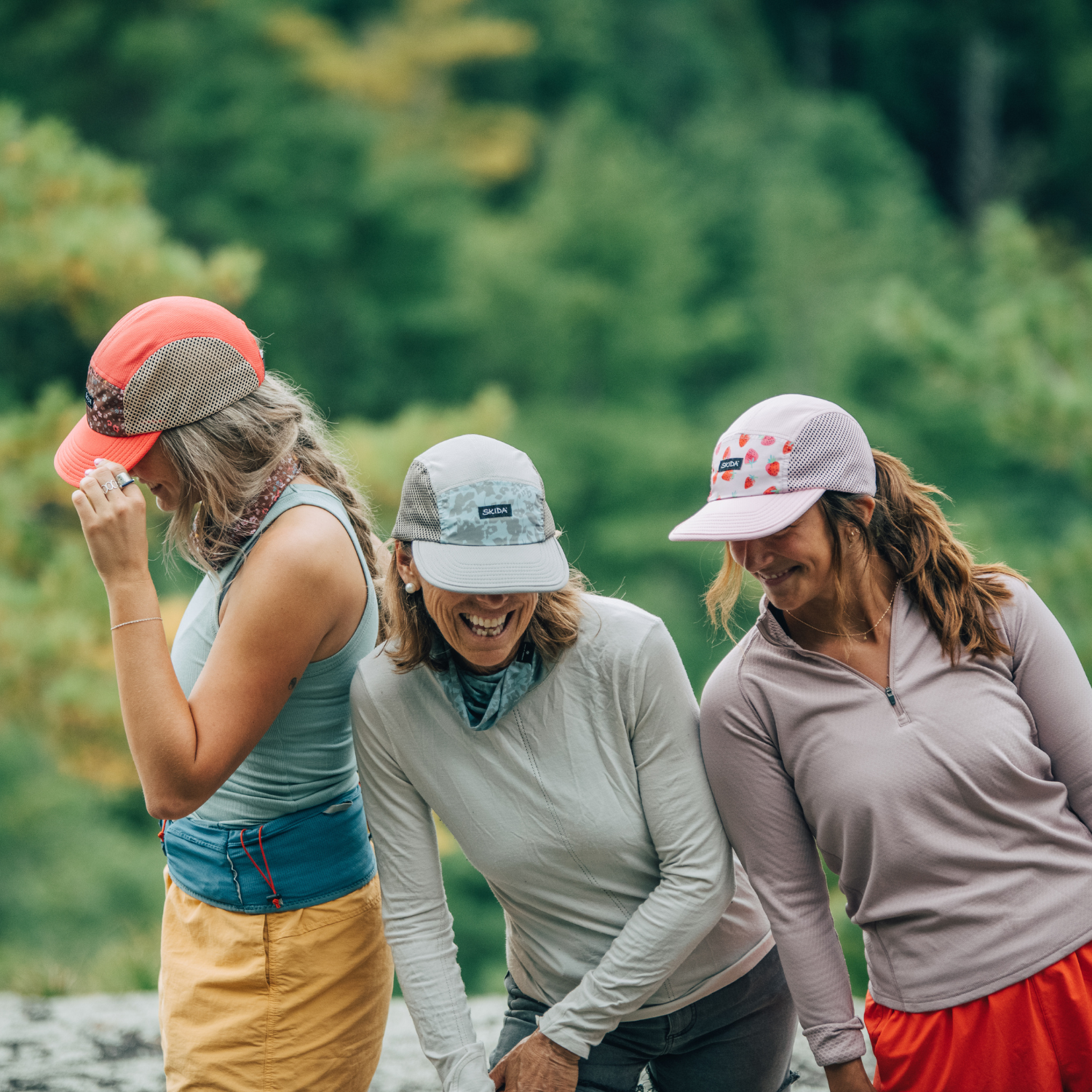 Three women wearing Skida hats