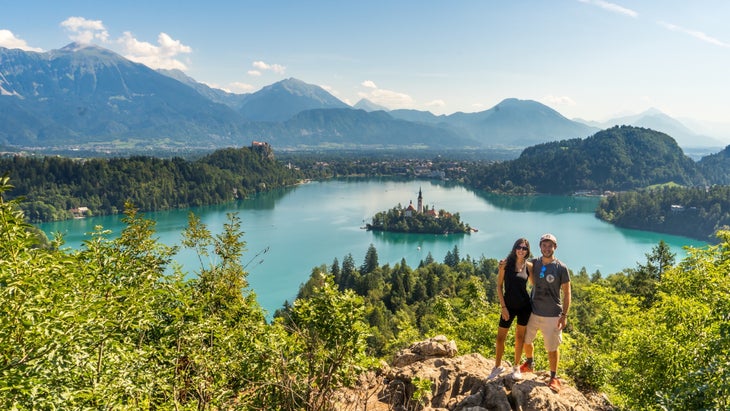 A couple poses above a lake 