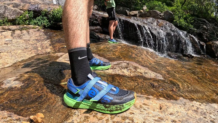 Closeup of blue Teva Aventrail trail running shoes on waterfall hike