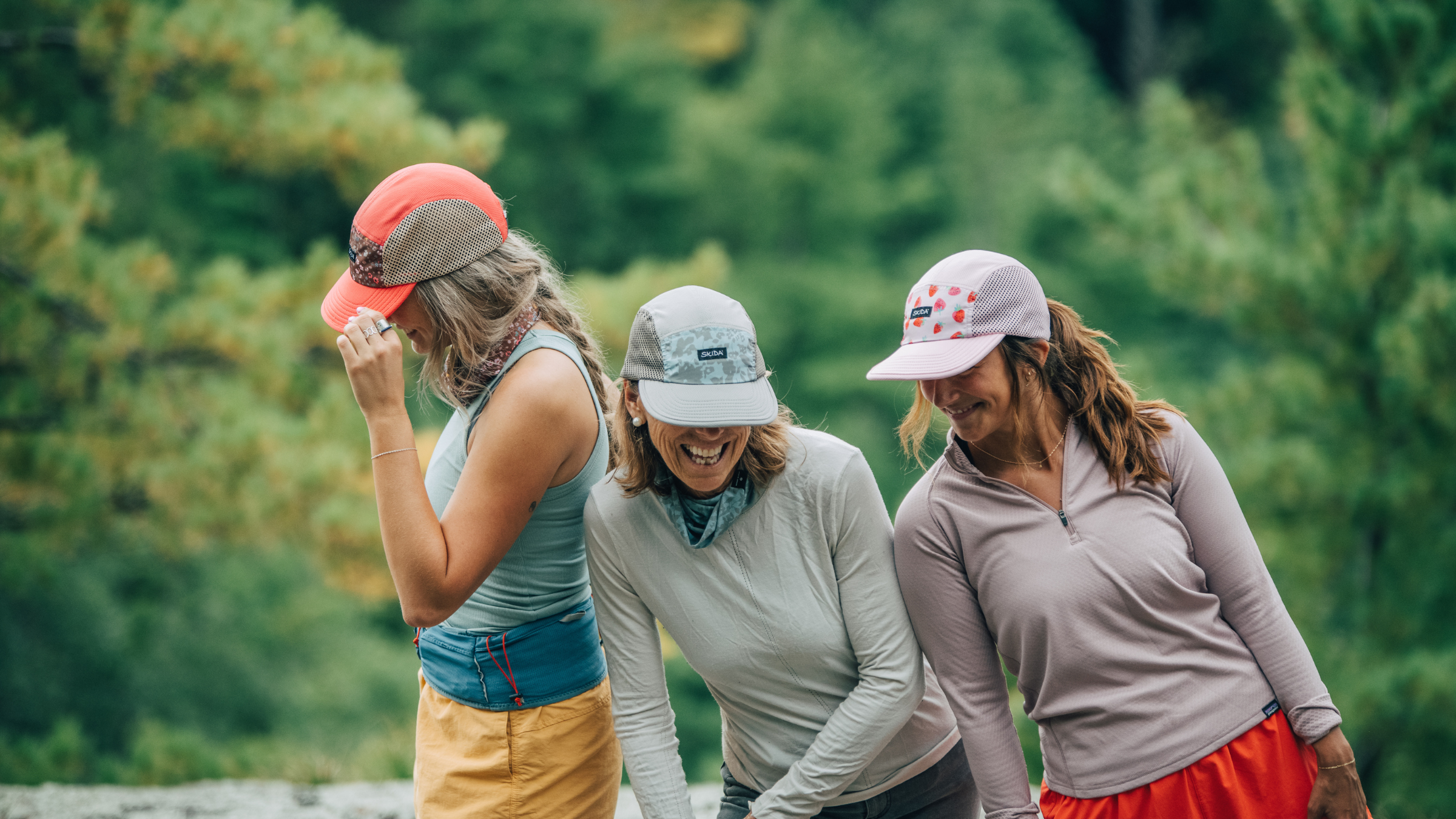 Three women wearing Skida hats
