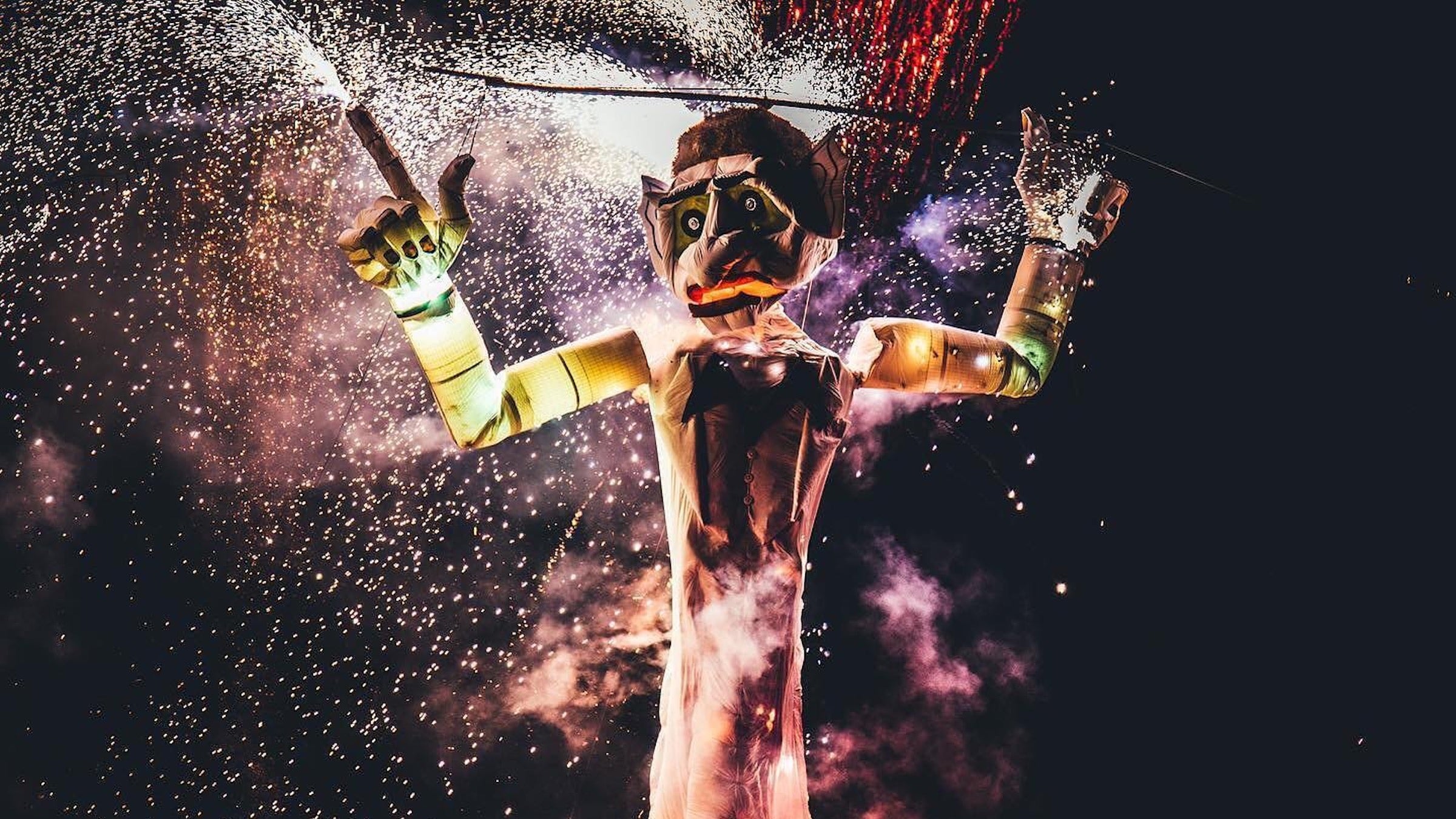 Zozobra, a giant puppet-like structure, burns while fireworks go off in the background