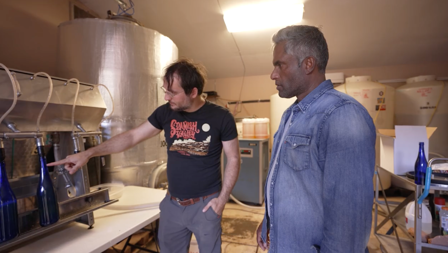 The general manager of Spanish Valley Vineyards walks chef Biju throw the bottling process.