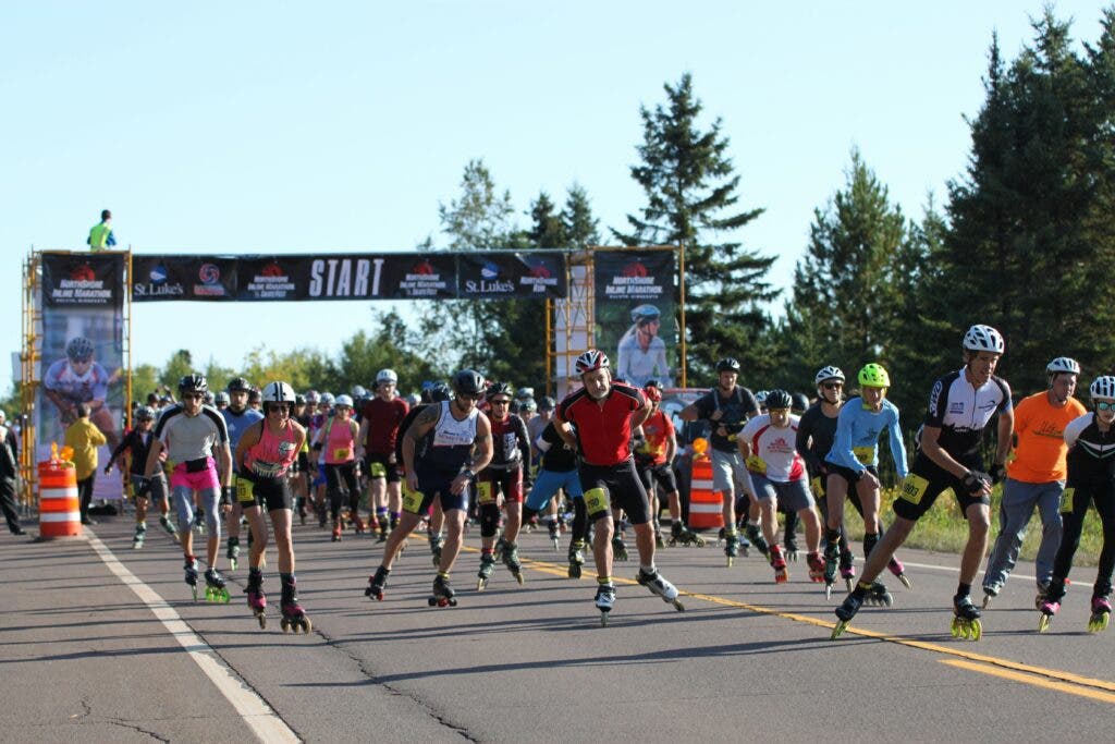 A group of people roller blading along an asphalt road.