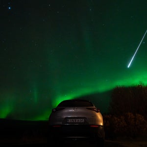 fireball streaking across green night sky over car