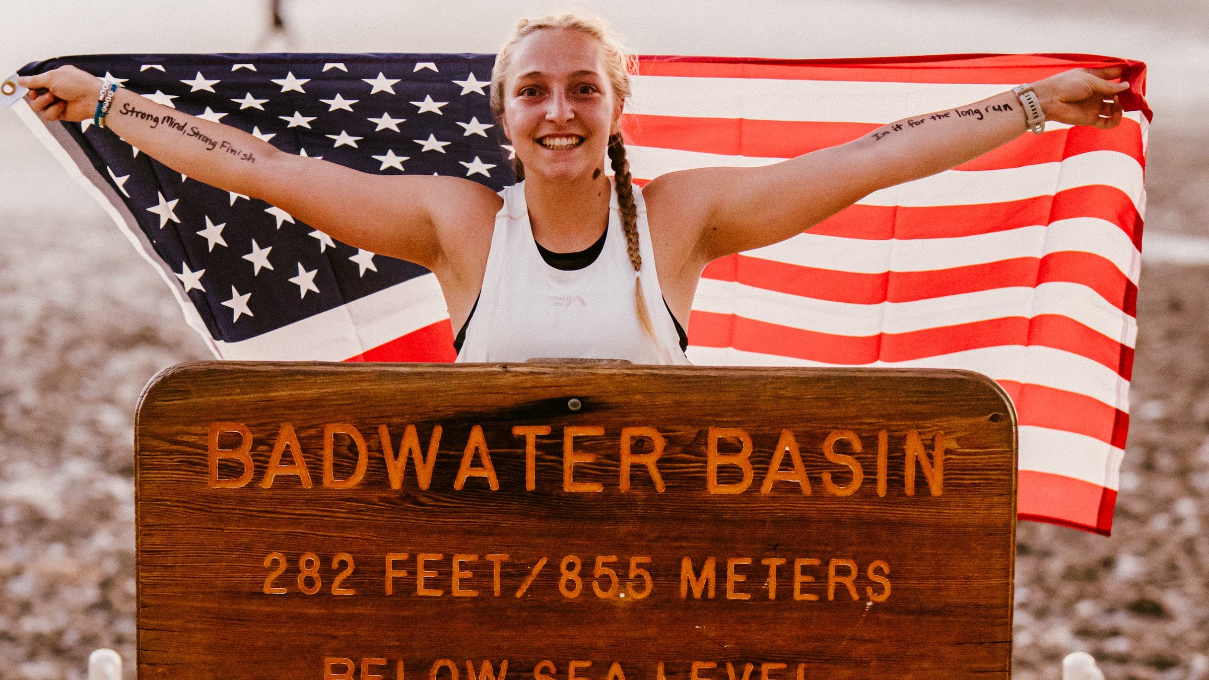 runner posing with american flag at badwater basin sign