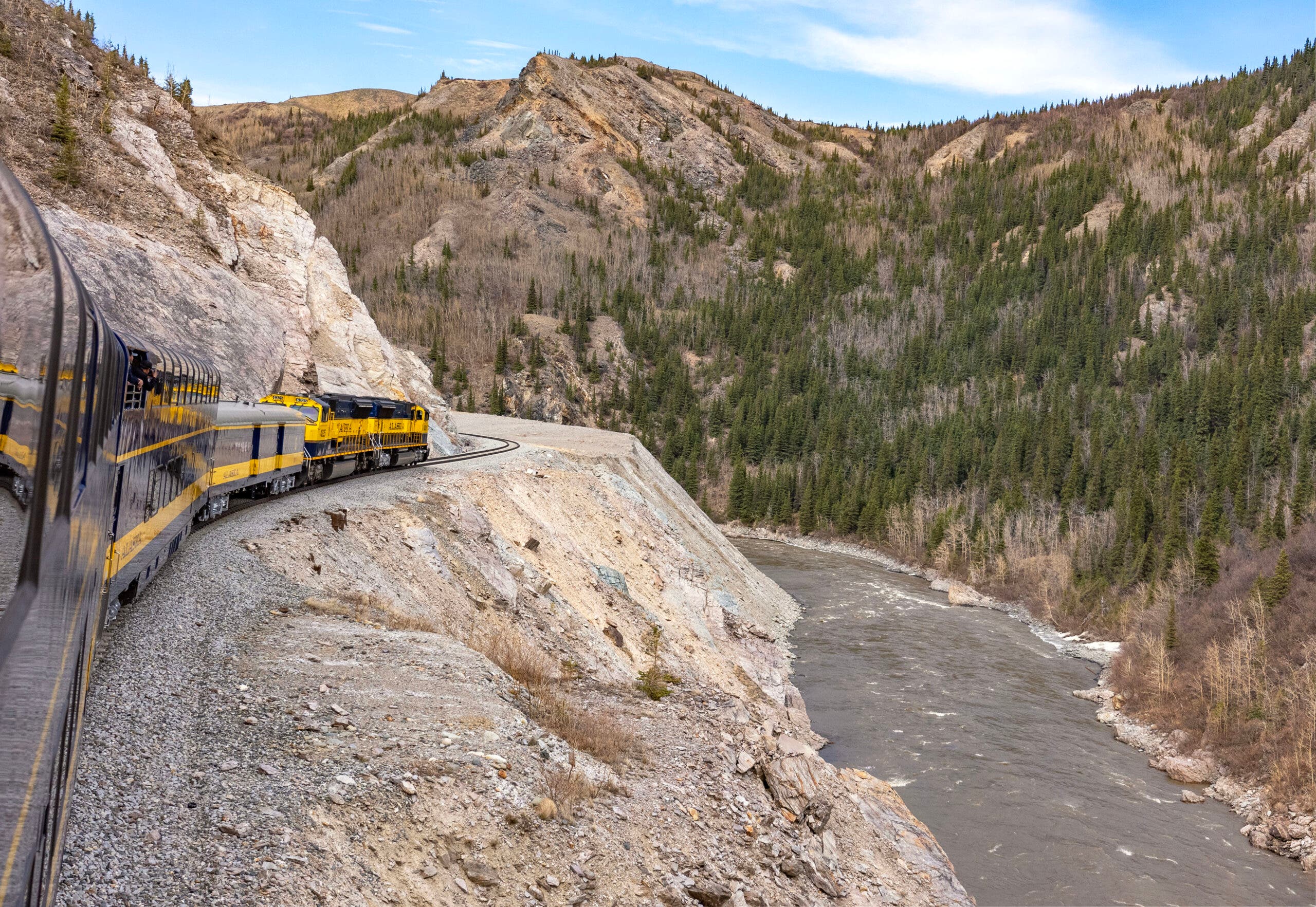 The Alaska Railroad's Denali Star Star train is on the edge of a river running through Denali National Park and Preserve in Alaska.
