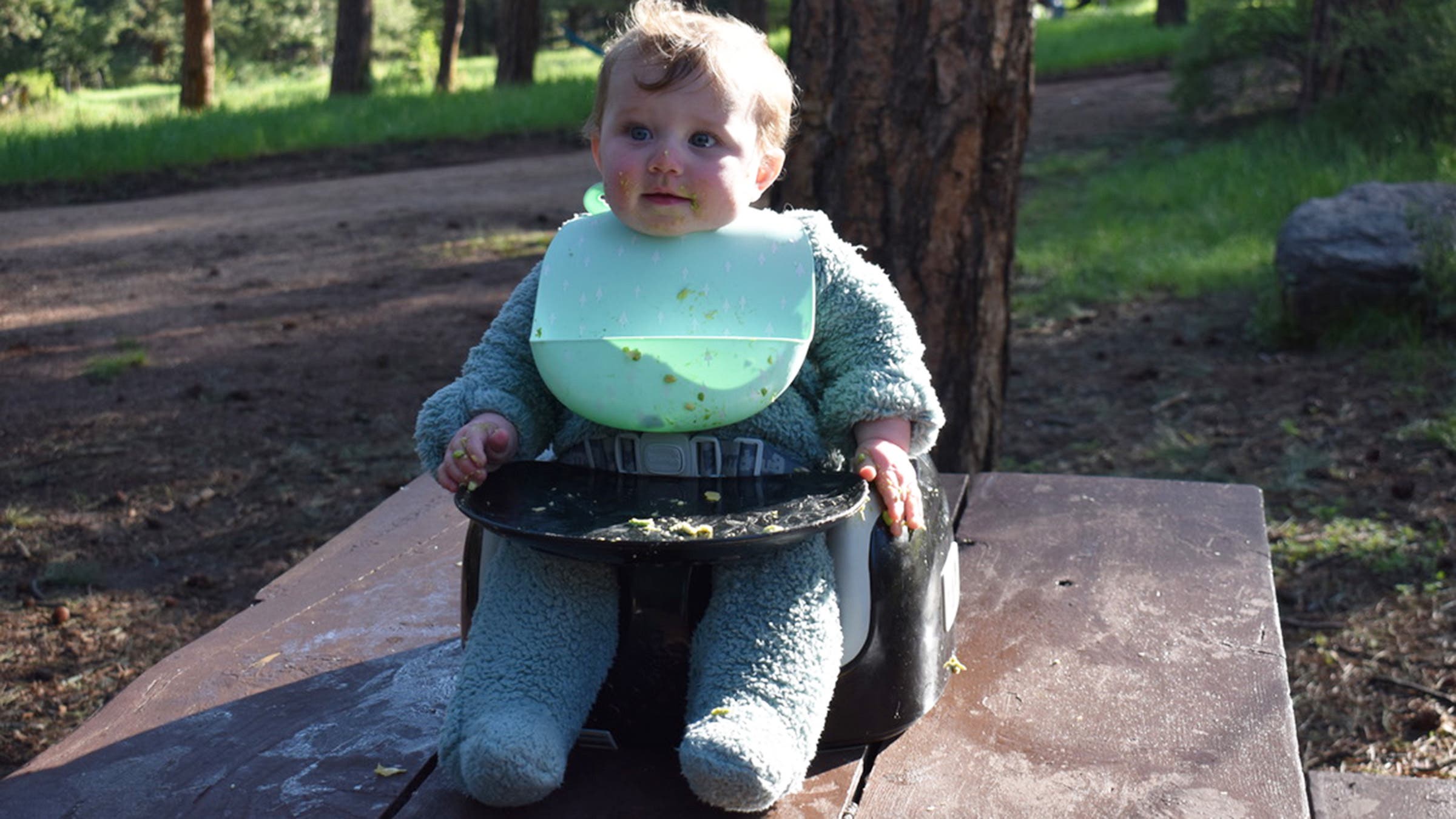 Baby sitting in booster seat on picnic table 