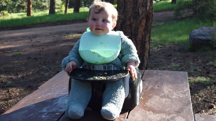 Baby sitting in booster seat on picnic table