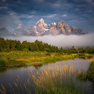 Stunning mountain scene in Grand Teton National Park with fog at the base of the mountains.