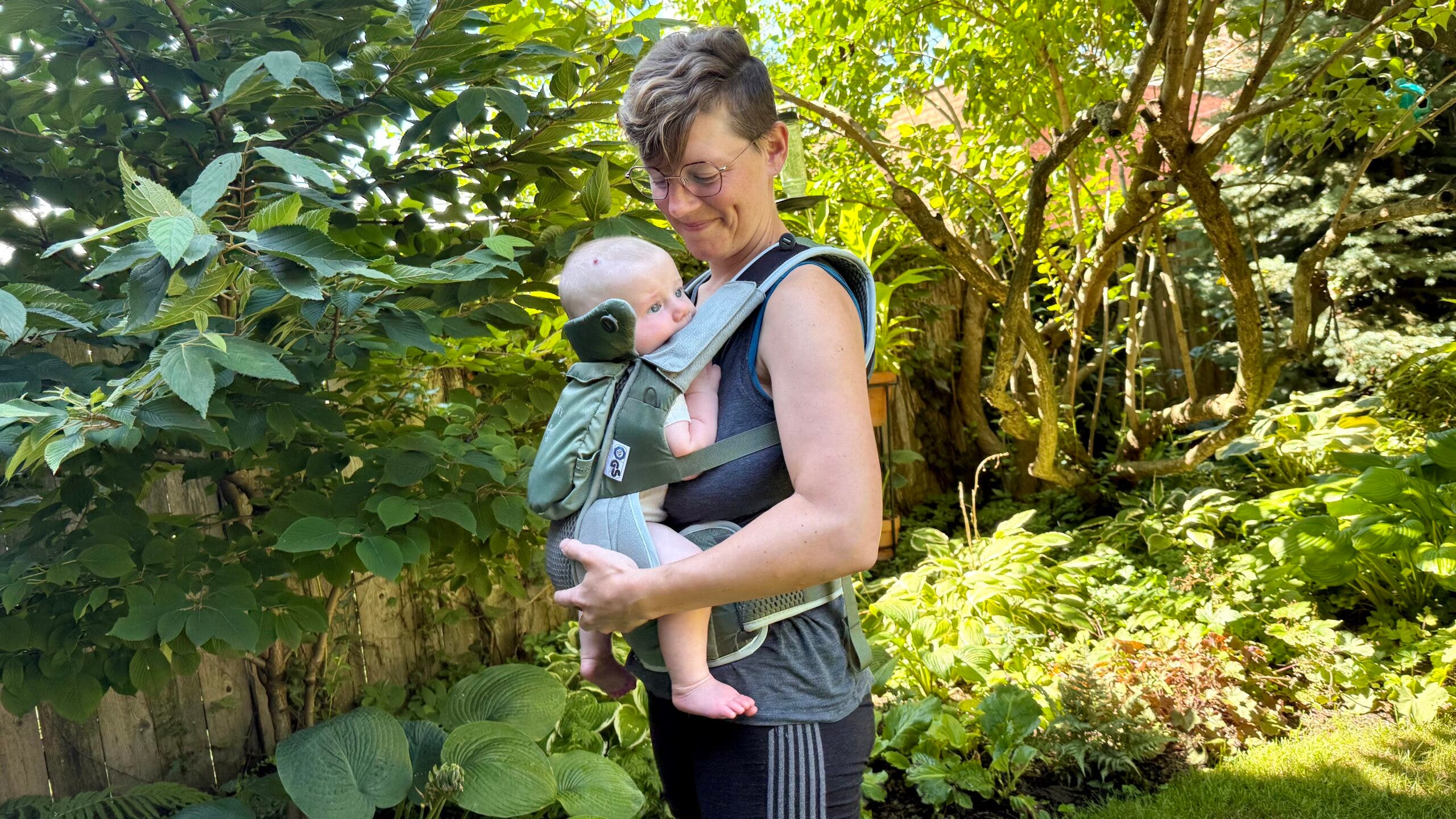 Woman carrying baby in carrier in garden