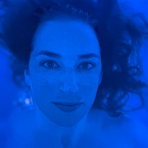 close up of a woman's face in blue light with her hair floating behind her