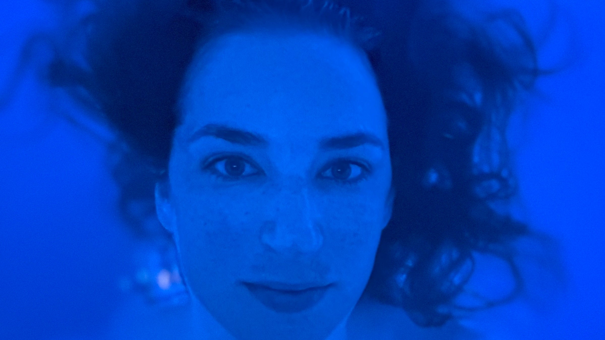 close up of a woman's face in blue light with her hair floating behind her