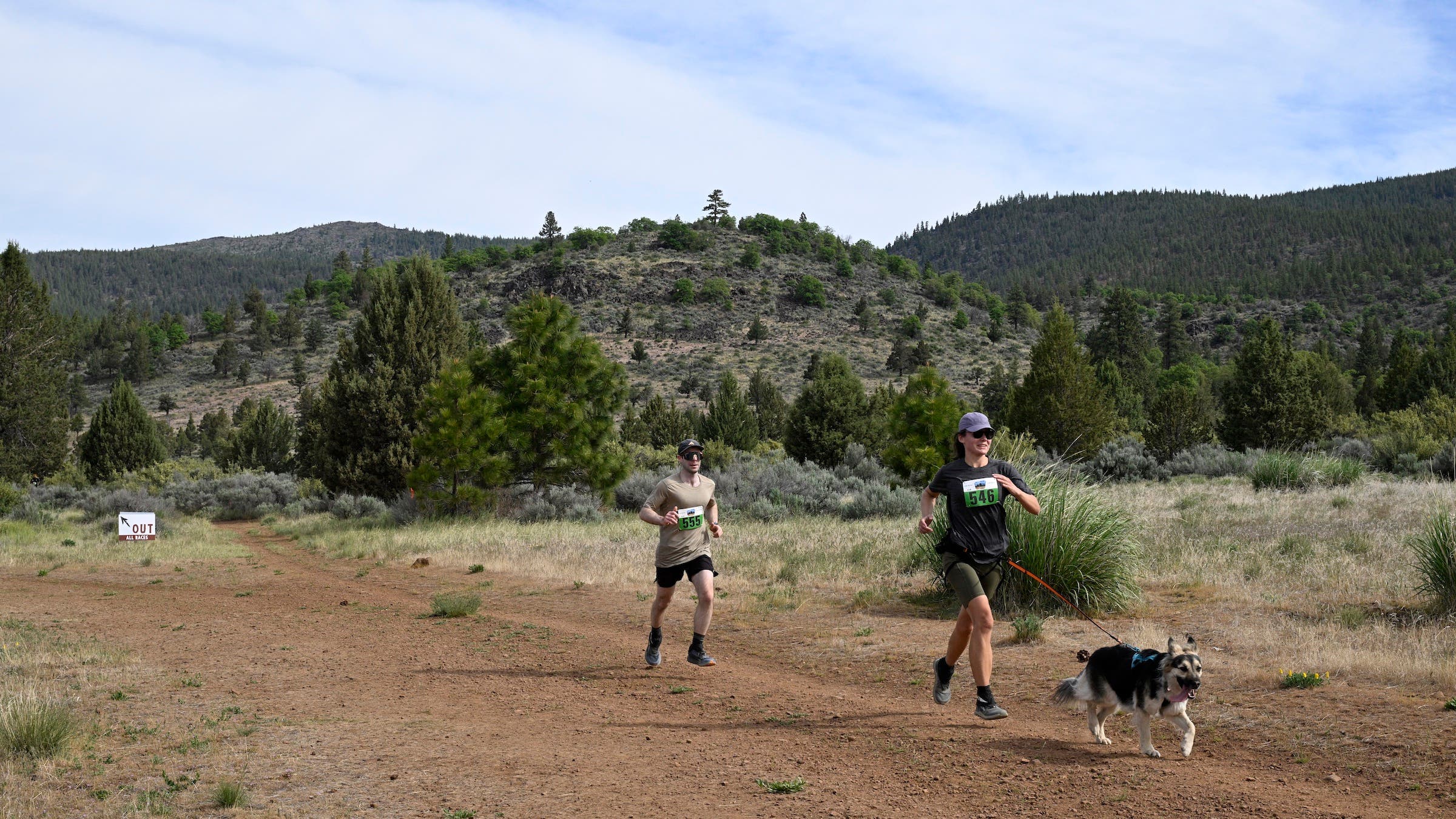 two people trail running with a dog