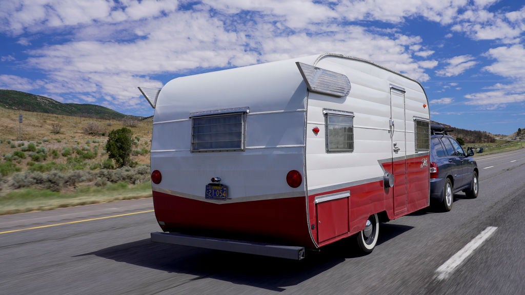 A vintage camper rolls down the highway