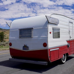 A vintage camper rolls down the highway