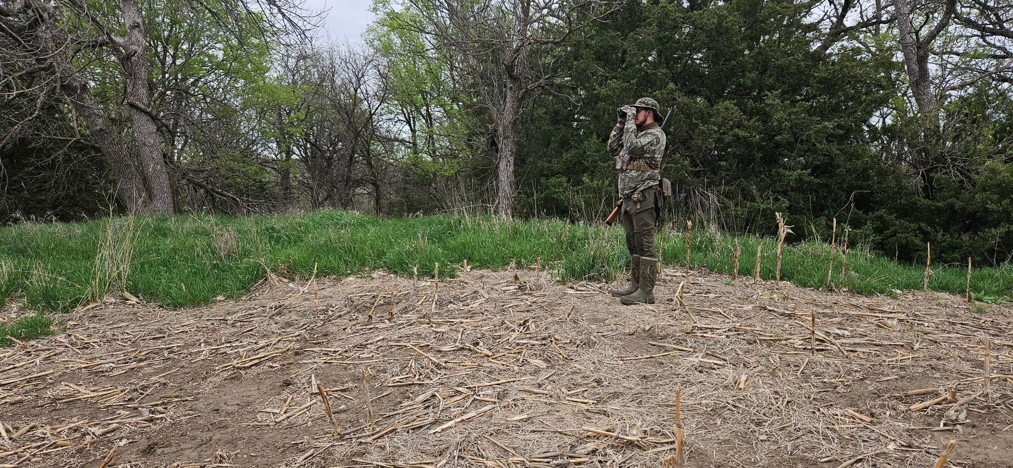 Man in camo looking through binoculars