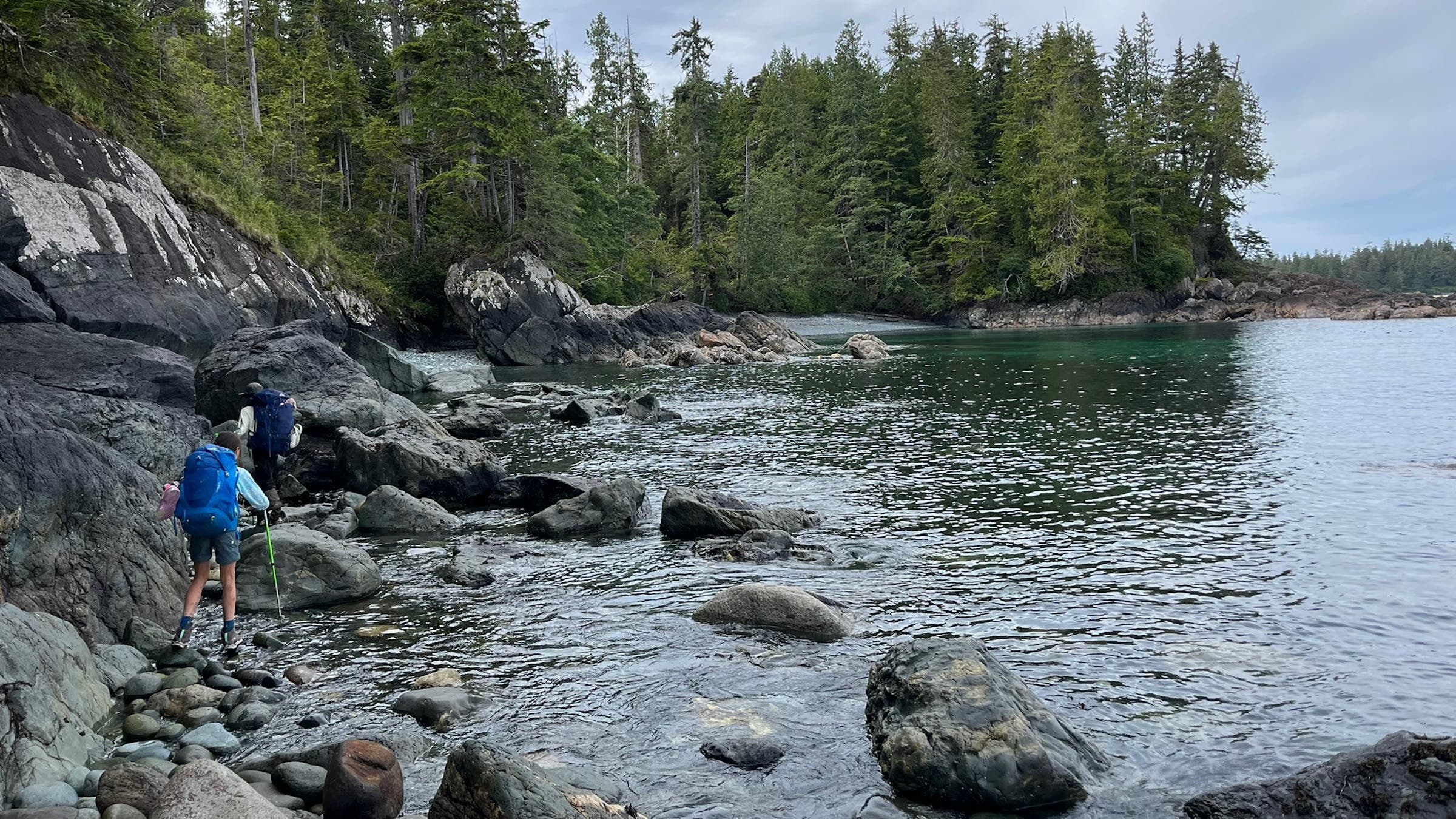 two hikers on rocks along water