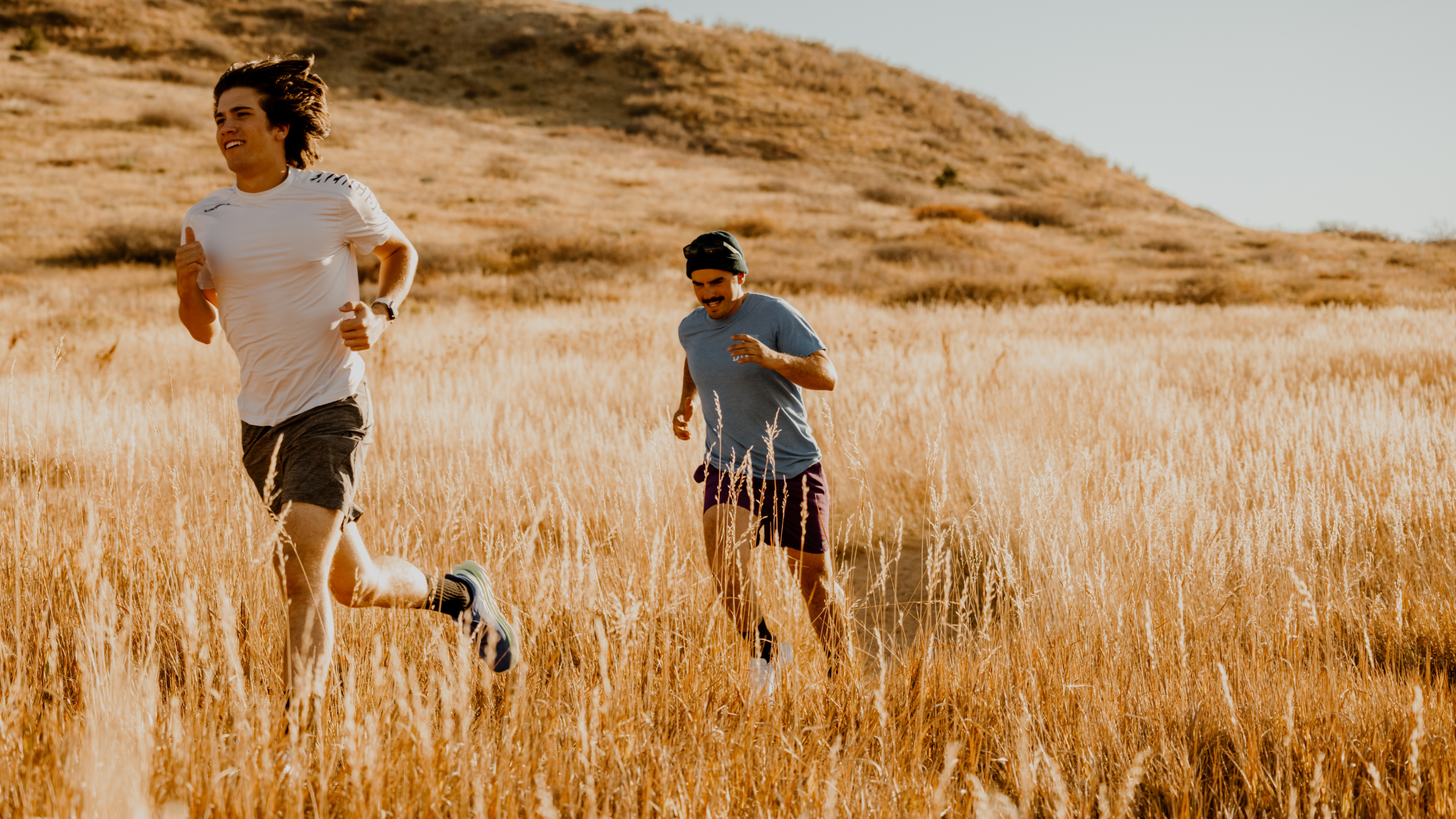 two men running in the mountains, one leading the pace wile the other tries to keep up