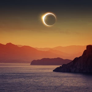 A total solar eclipse over water and mountains