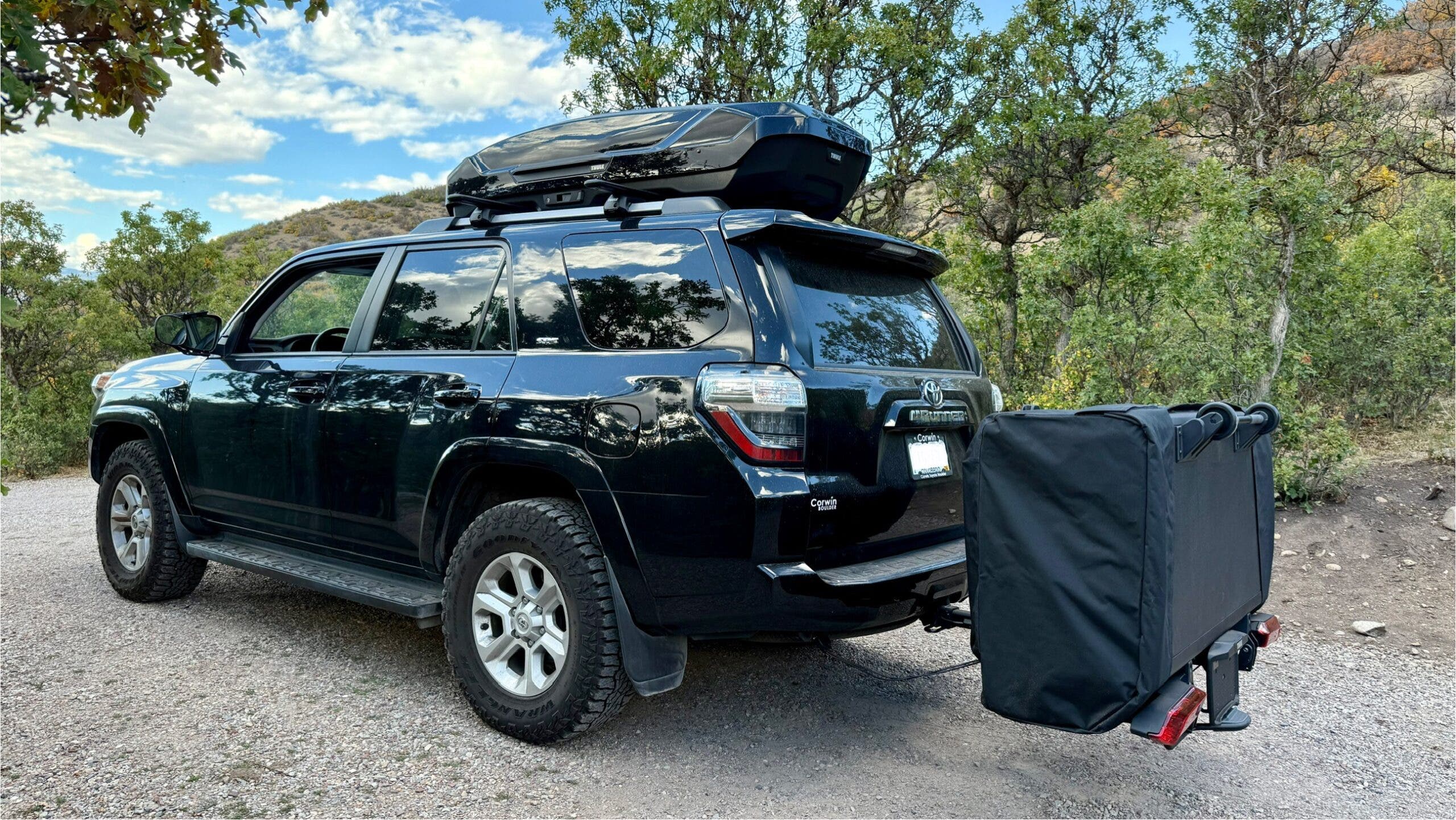 Black Toyota 4Runner with Thule Outset folded up and attached to hitch at camping site