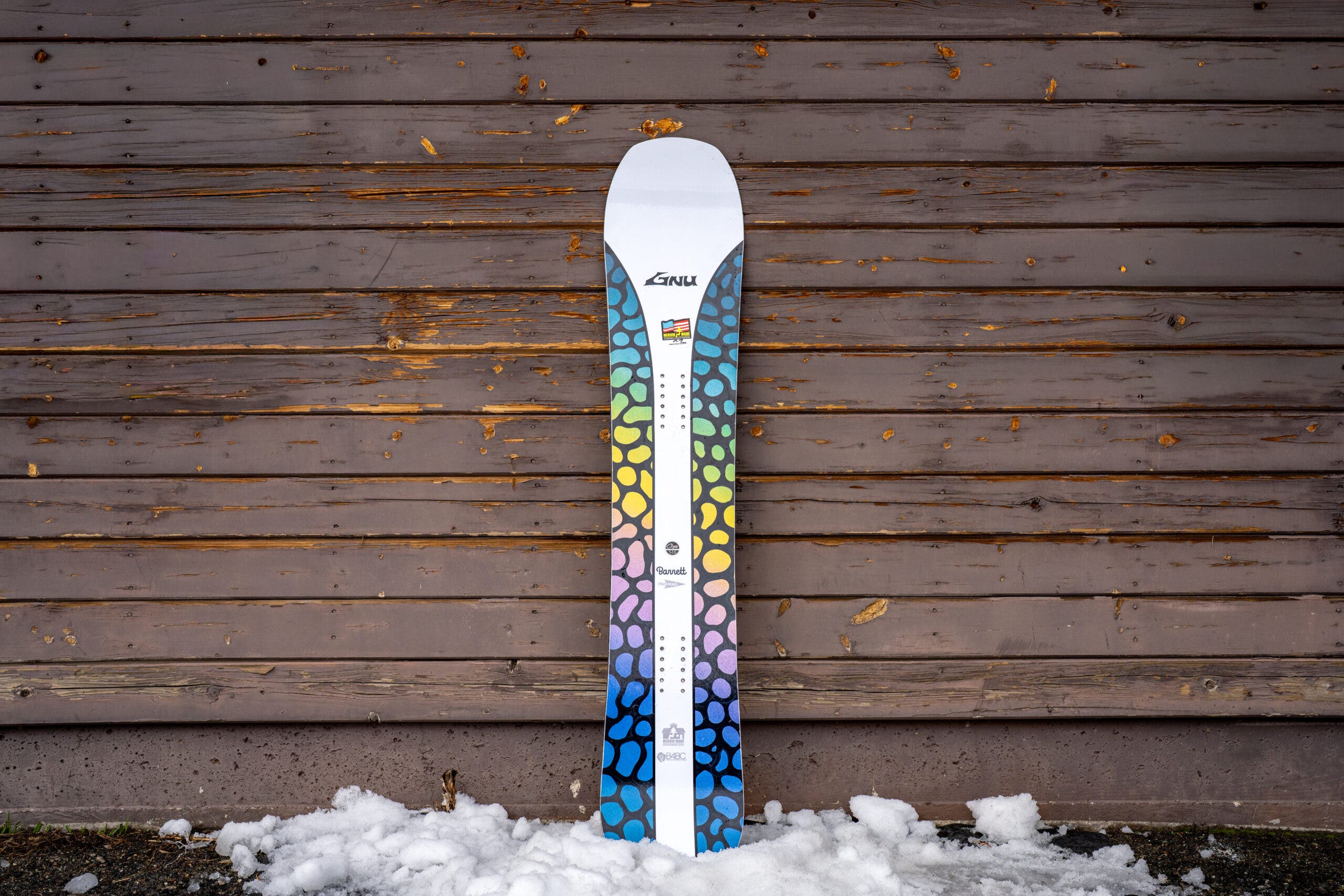 Gnu Barrett snowboard leaning against a weathered building