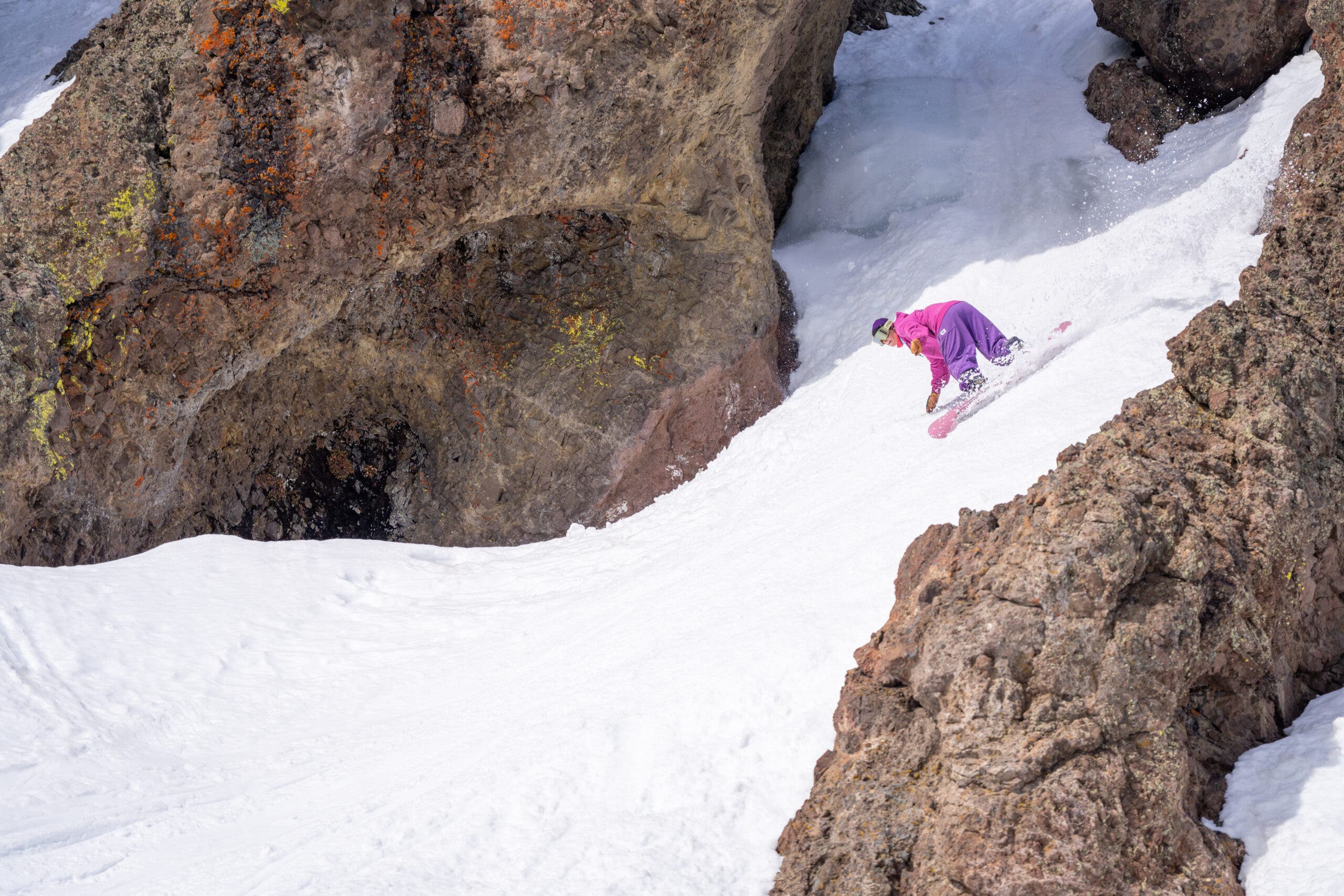 female snowboarder rides through chute