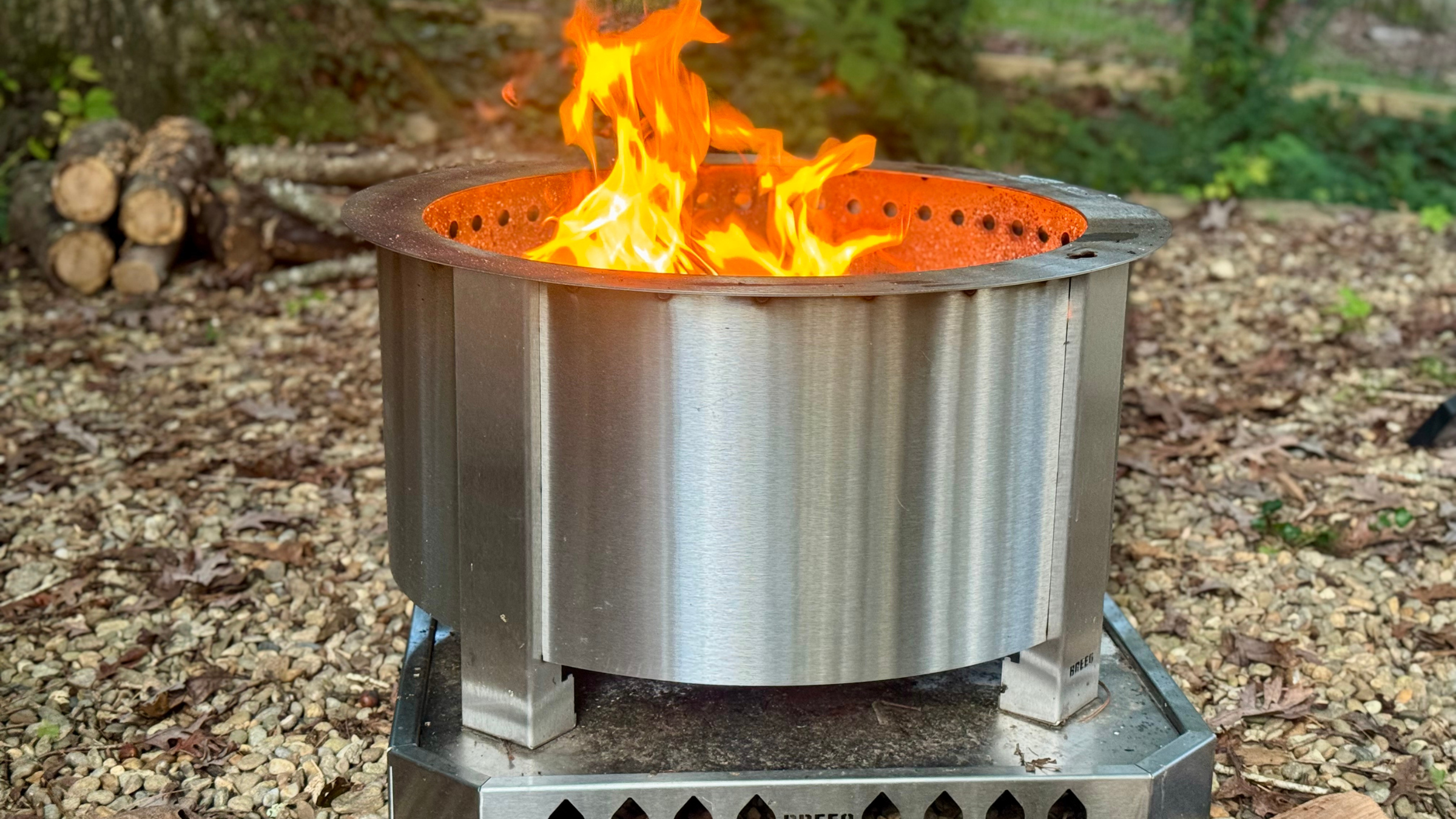 Breeo X Series stainless steel smokeless fire pit in a backyard with a fire inside