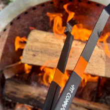 large metal tongs held over fire in smokeless fire pit in backyard
